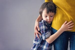 Sad little child, boy, hugging his mother at home