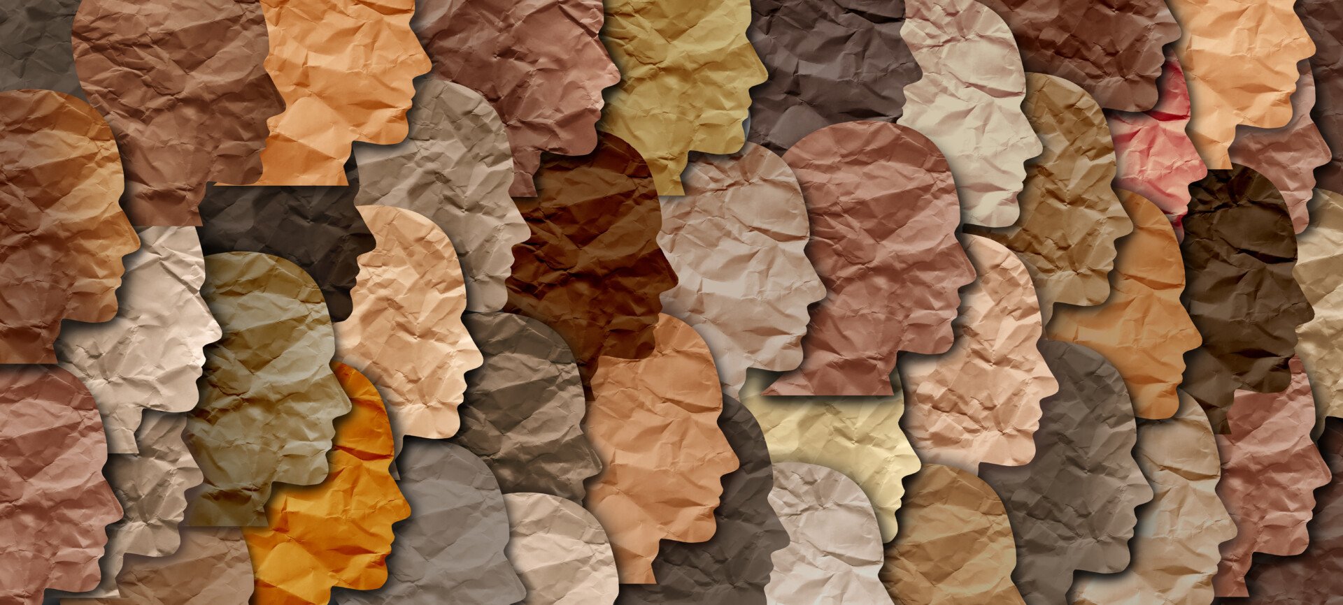 a wall of paper outlines of faces in different skin colours