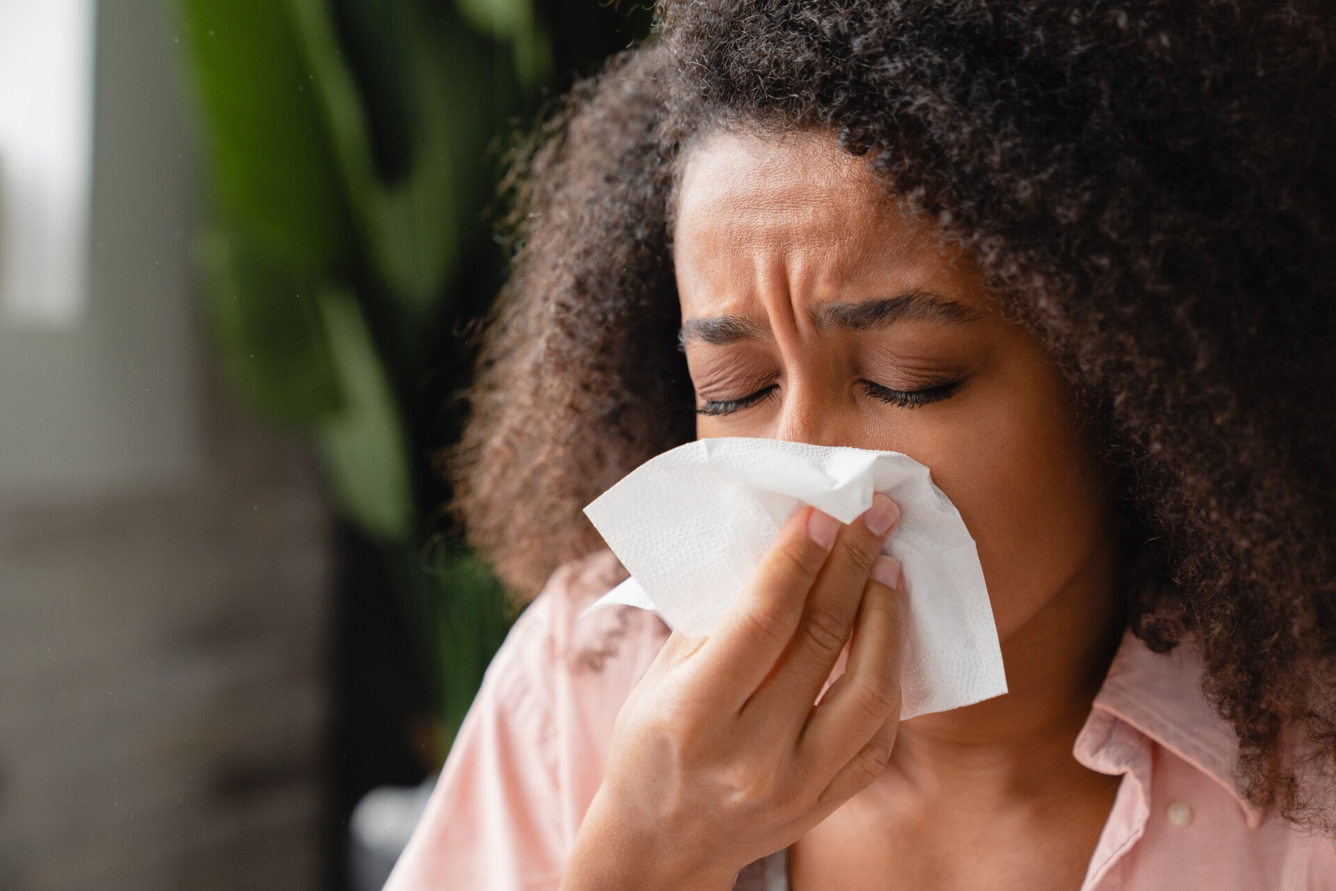 A woman covering her sneeze with a tissue which is a type of folkway.