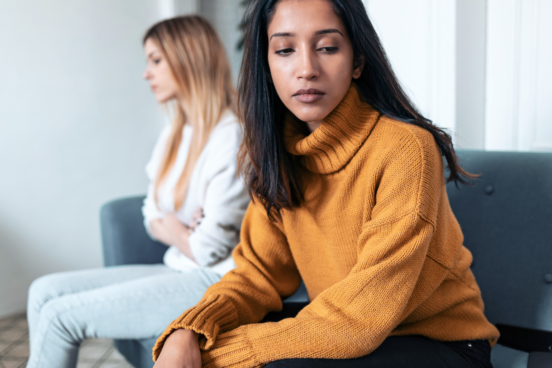 Two upset friends not talking to each other after fight on the sofa