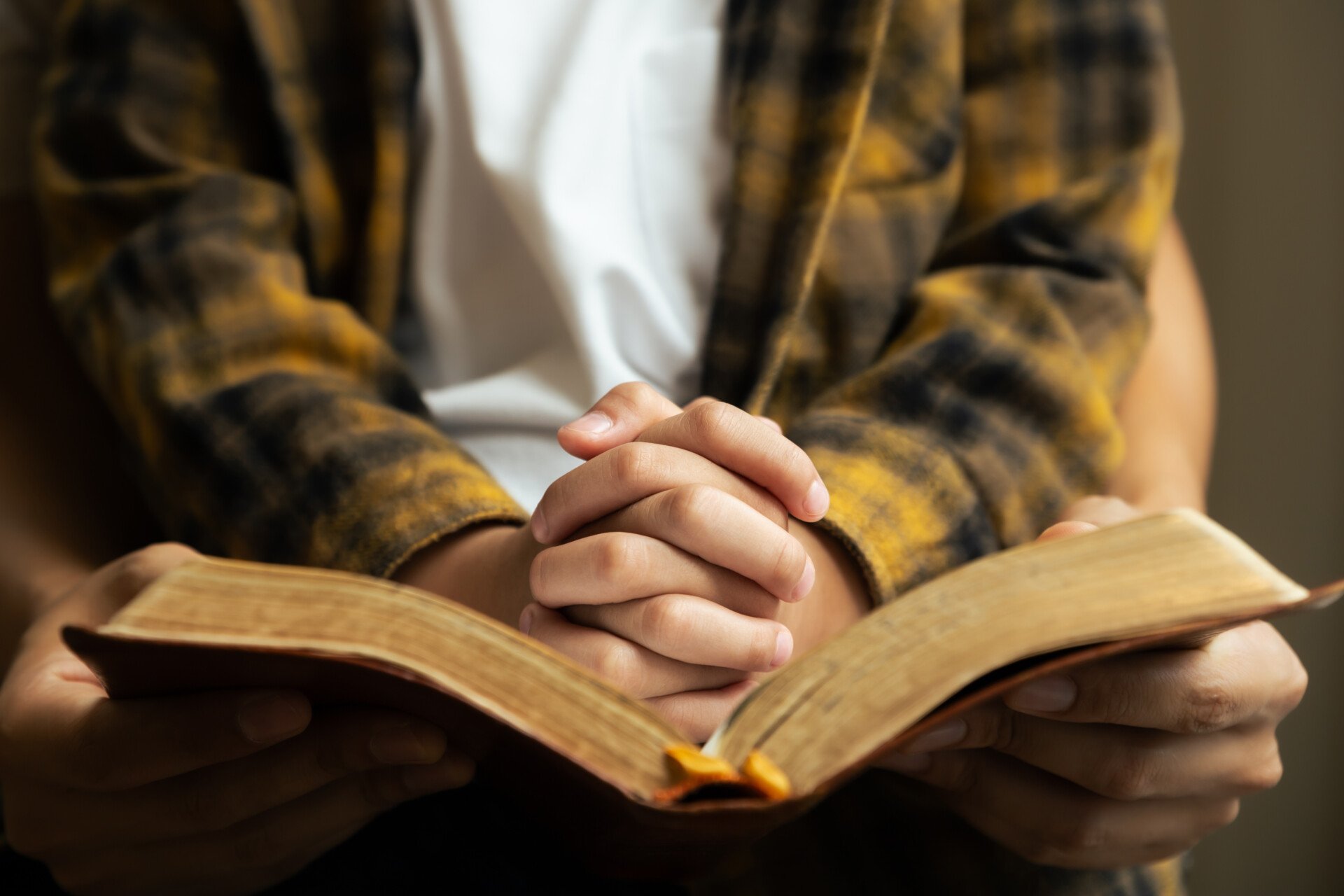 Little boy and his father praying and read Bible by the window in library and church,