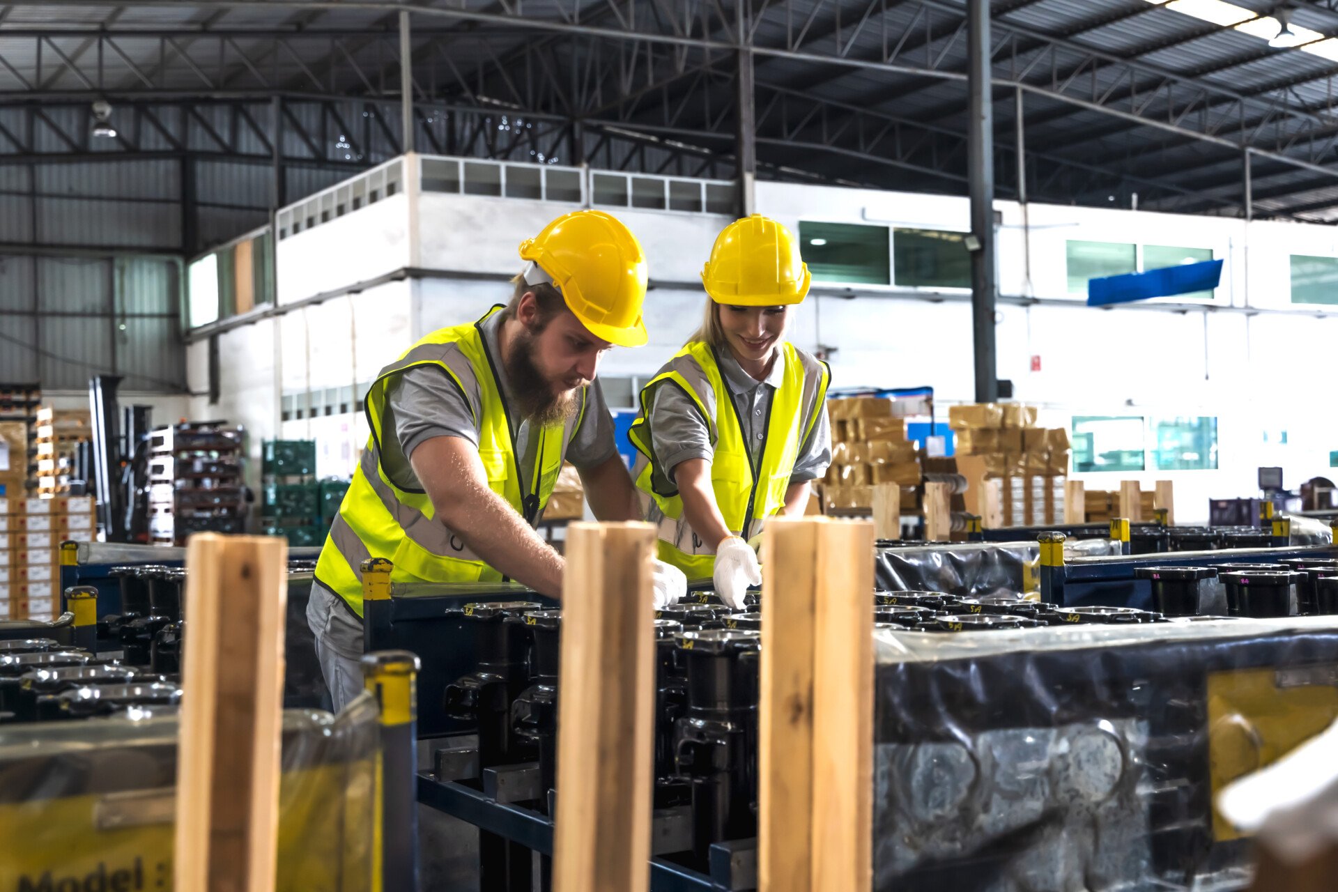 Factory worker man and woman working together in auto parts manufacturing warehouse