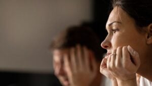 Close up of a parent's face looking anxiety, head in hands.