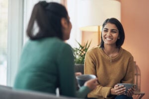 Shot of two women drinking coffee while sitting together at home.