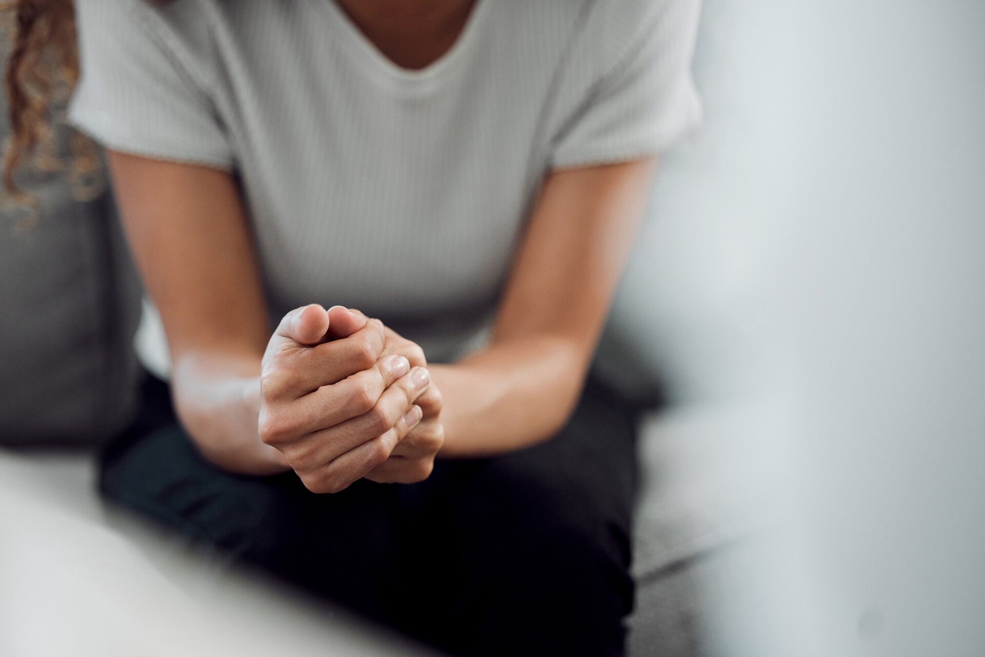 a woman sat on a sofa grasping her hands together